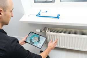 The technician checking the heating system in the boiler room with tablet in hand